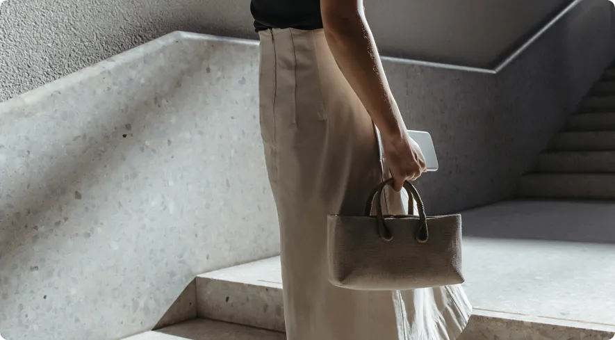 Shopper walking down a staircase carrying a handbag and a phone