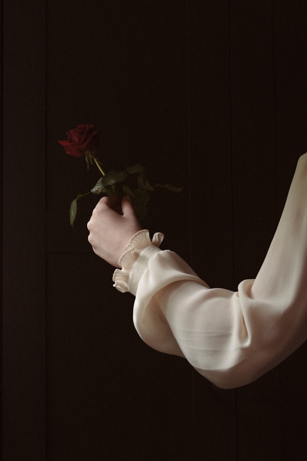 a woman in a white dress holding a red rose