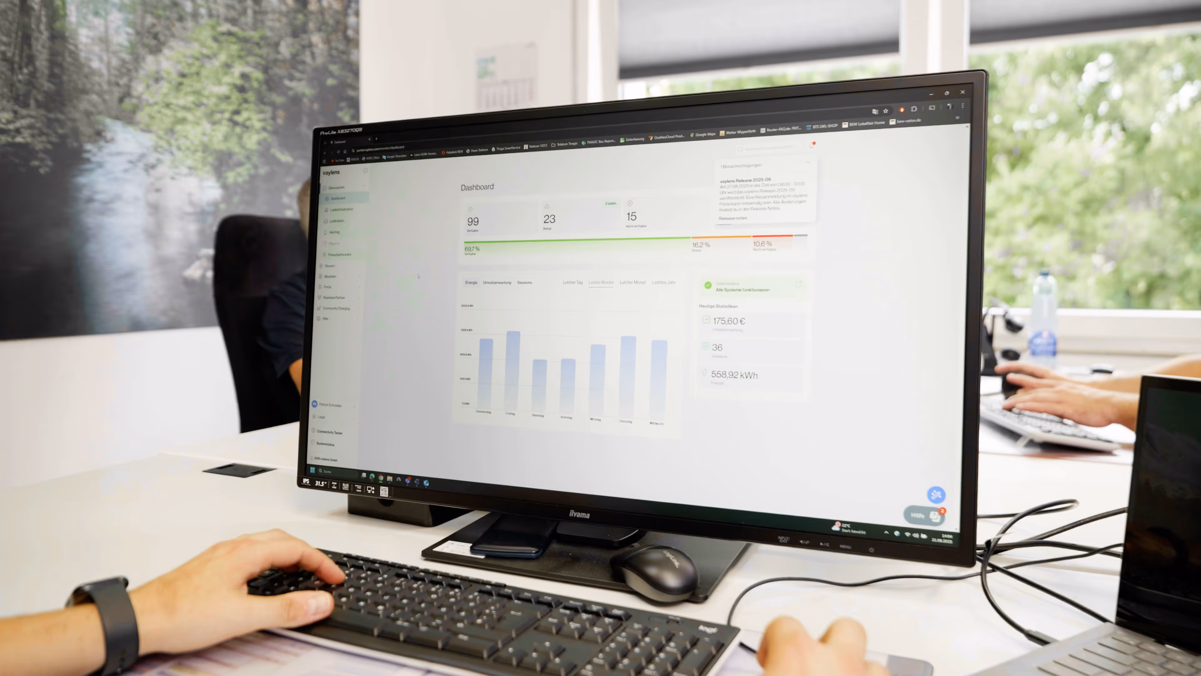 Computer screen displaying an energy management dashboard with charts and usage statistics, hands typing on a keyboard in an office setting.