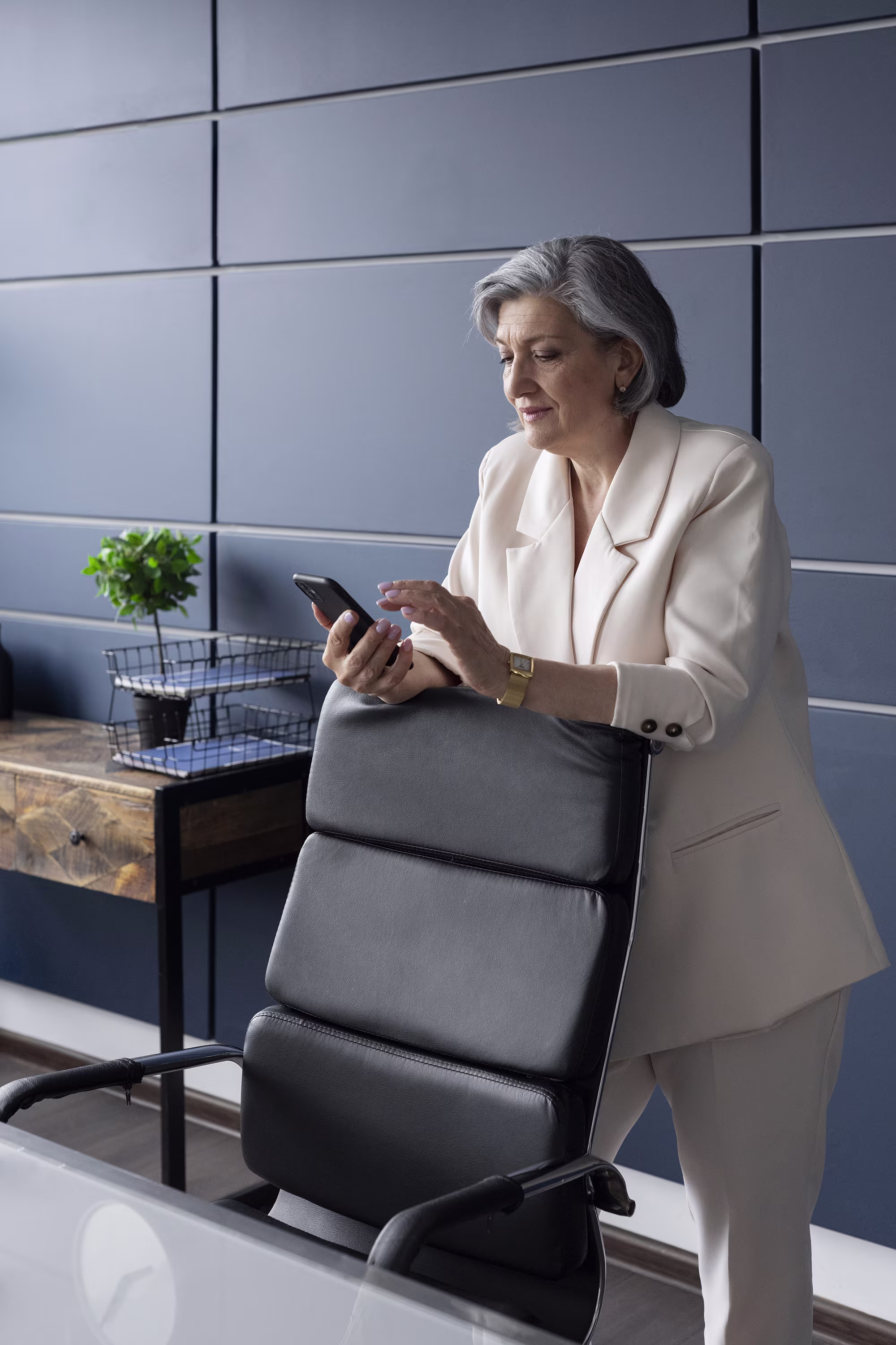 Frau steht vor Schreibtischstuhl mit Handy in der Hand zur Visualisierung von LinkedIn Networking
