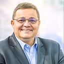 Portrait d’un homme en costume avec lunettes, souriant, en contexte professionnel