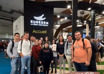 Groupe d'étudiants rassemblés devant le stand d'Eureden avec l'inscription "La Terre nous Réunit" lors d'un événement agricole.