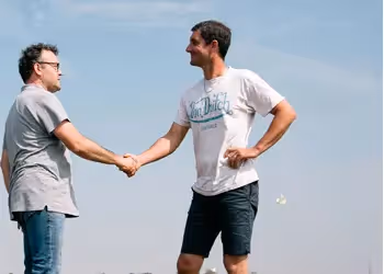 Deux agriculteurs se serrant la main dans un champ, illustrant la collaboration entre coopérateurs.