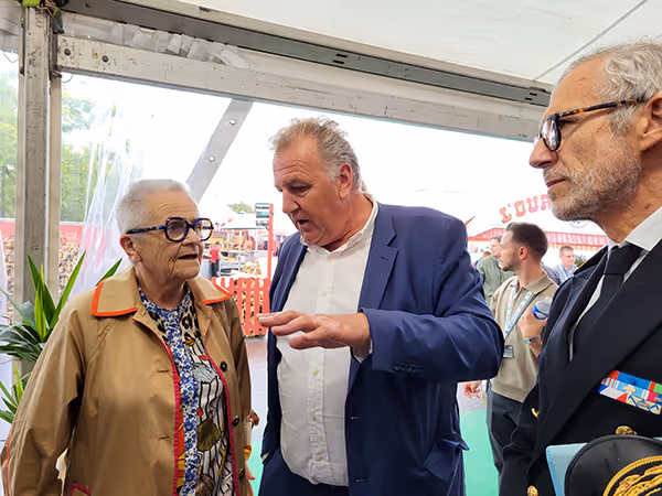 Échange entre trois responsables institutionnels lors d’un salon agricole, sous une tente événementielle
