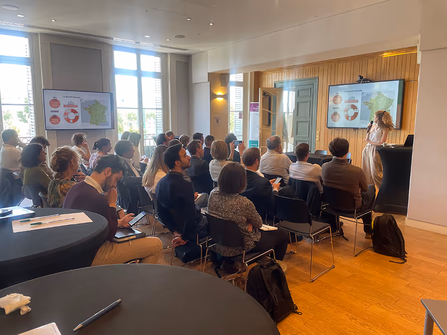 Conférence professionnelle dans une salle lumineuse, avec une intervenante présentant des données cartographiques à un public attentif.