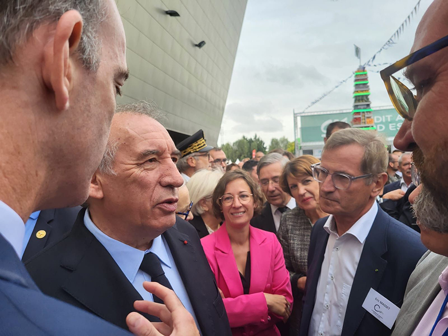 Échange entre élus et représentants d’organisations devant un bâtiment institutionnel, lors d’un événement officiel.