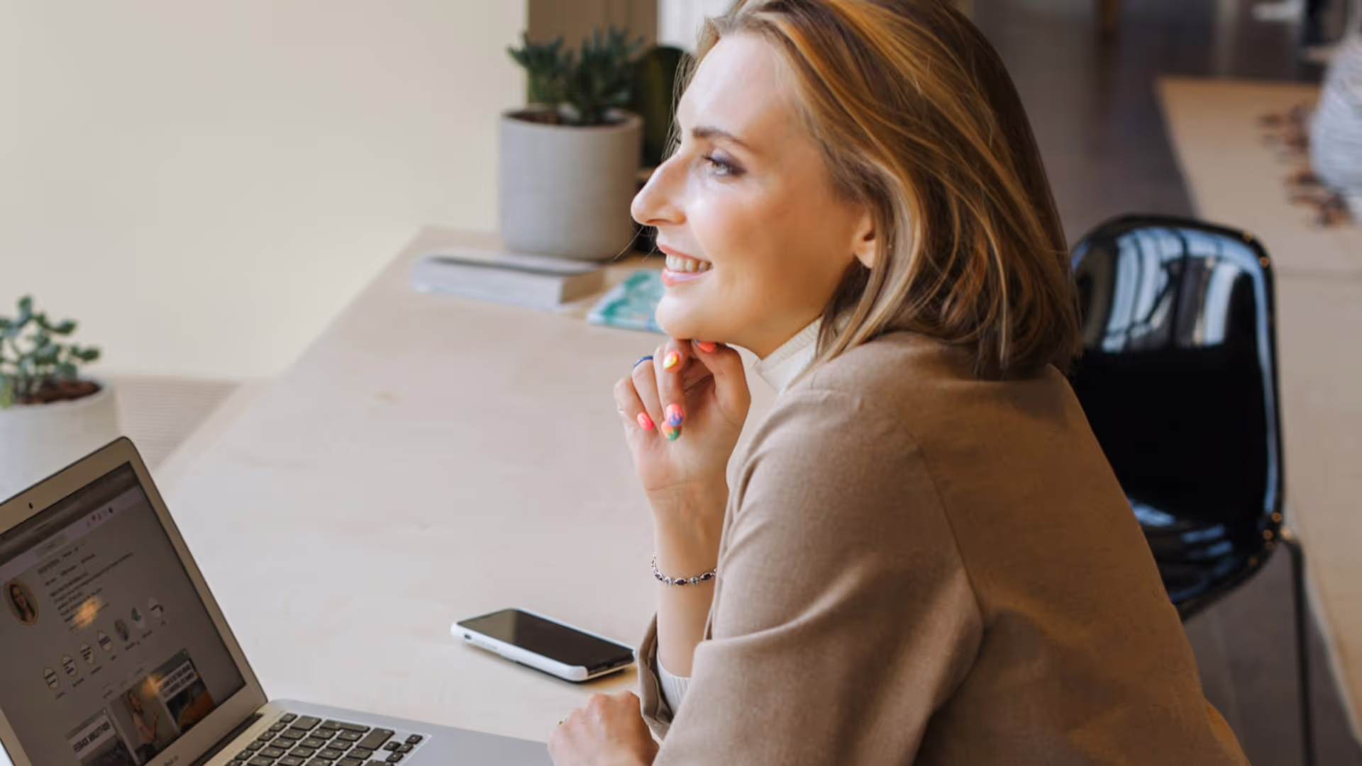Woman with laptop chatting across a desk.