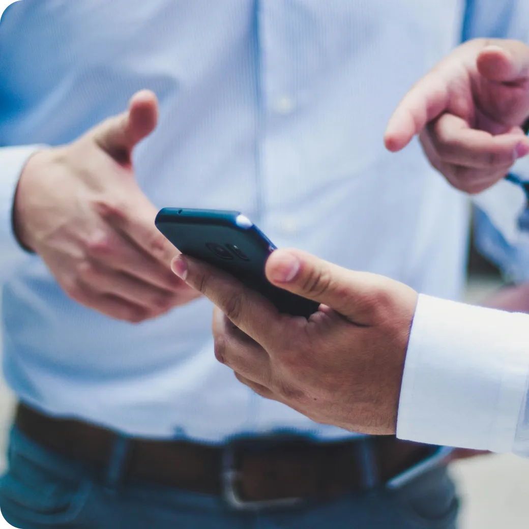 Two men reviewing information on a smartphone during a business discussion
