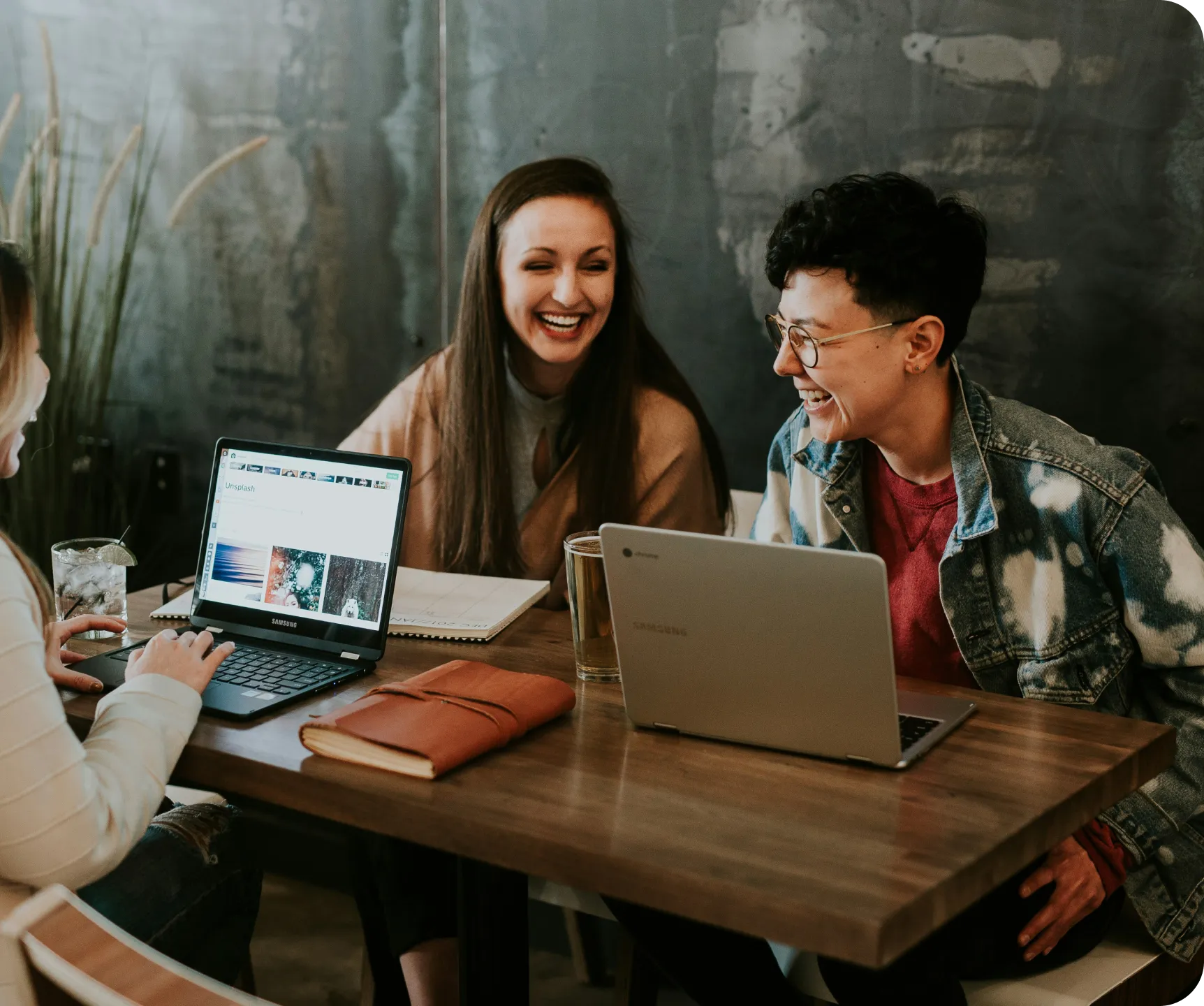 Three coworkers reviewing documents and laptop screens in a workspace