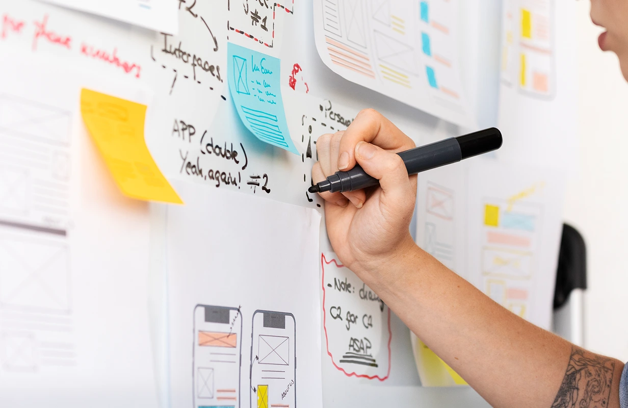 Designer writing notes on UX wireframes.