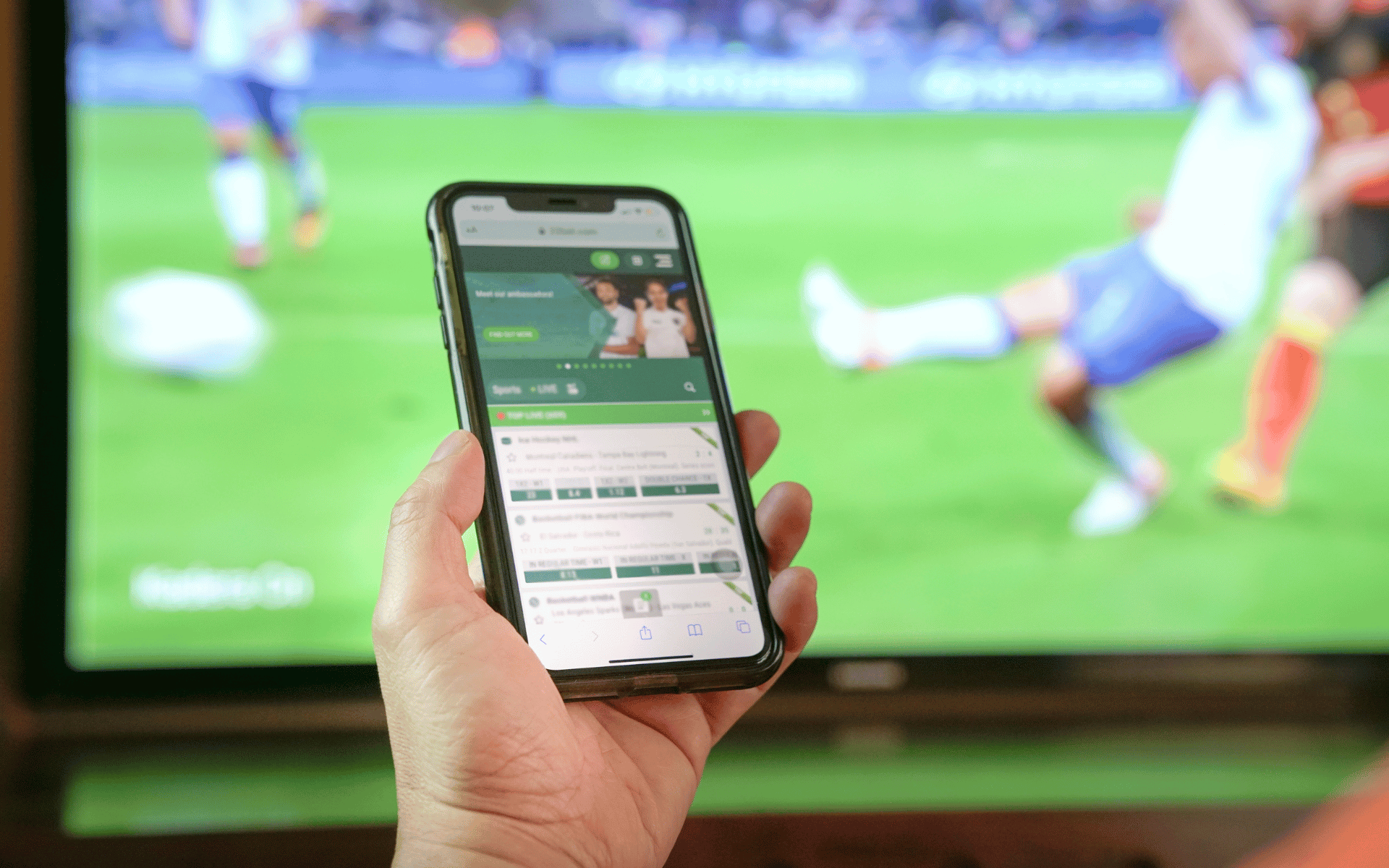 betting screen on phone in front of tv sports