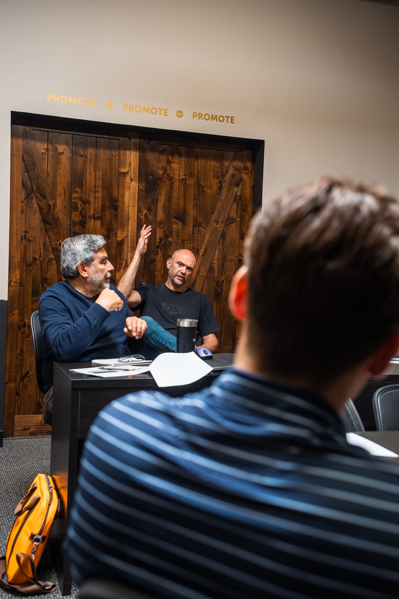 Teammate gesturing animatedly mid-discussion at the training day desk