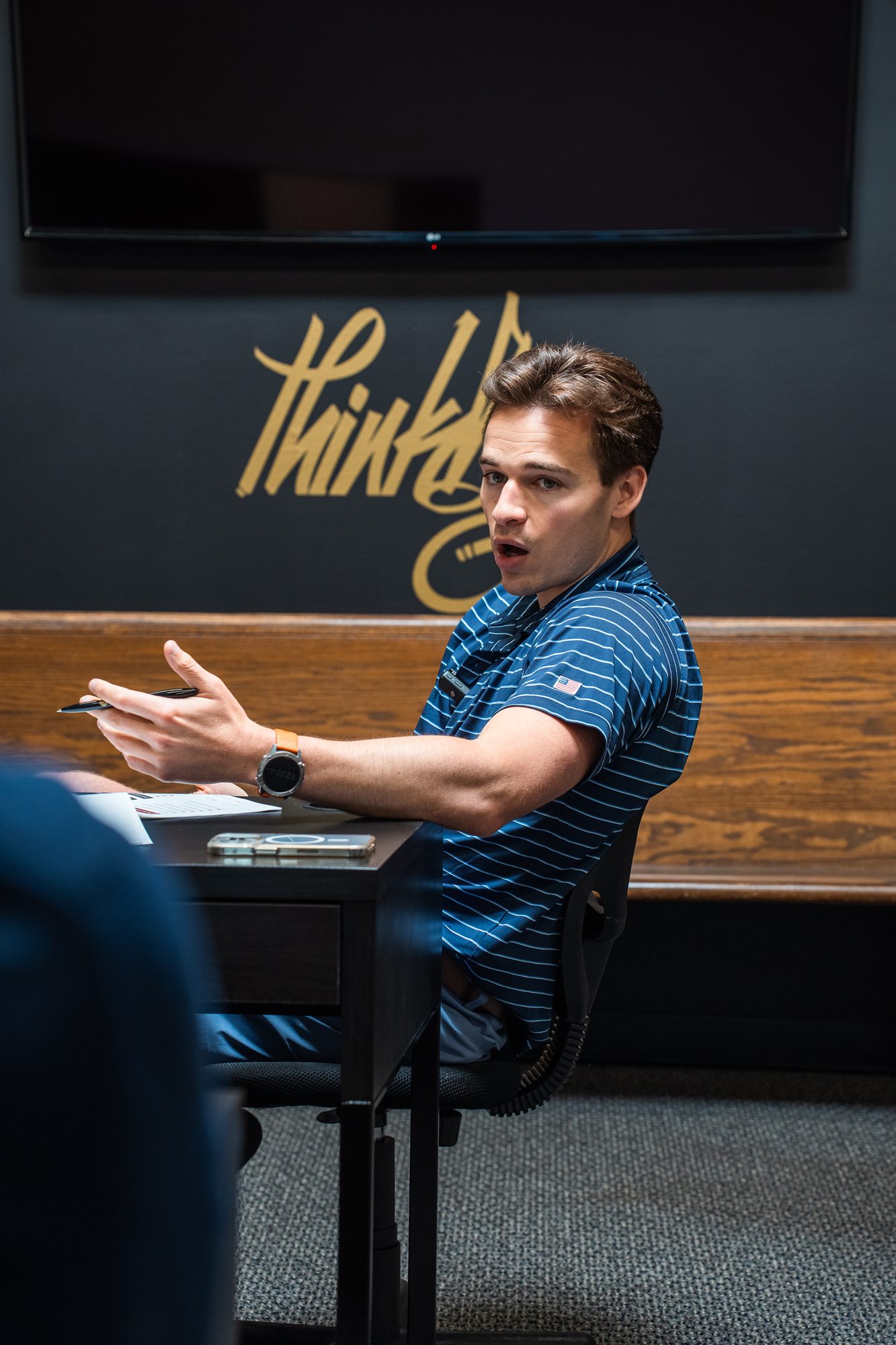 Young loan officer mid-sentence gesturing with an open hand at the desk