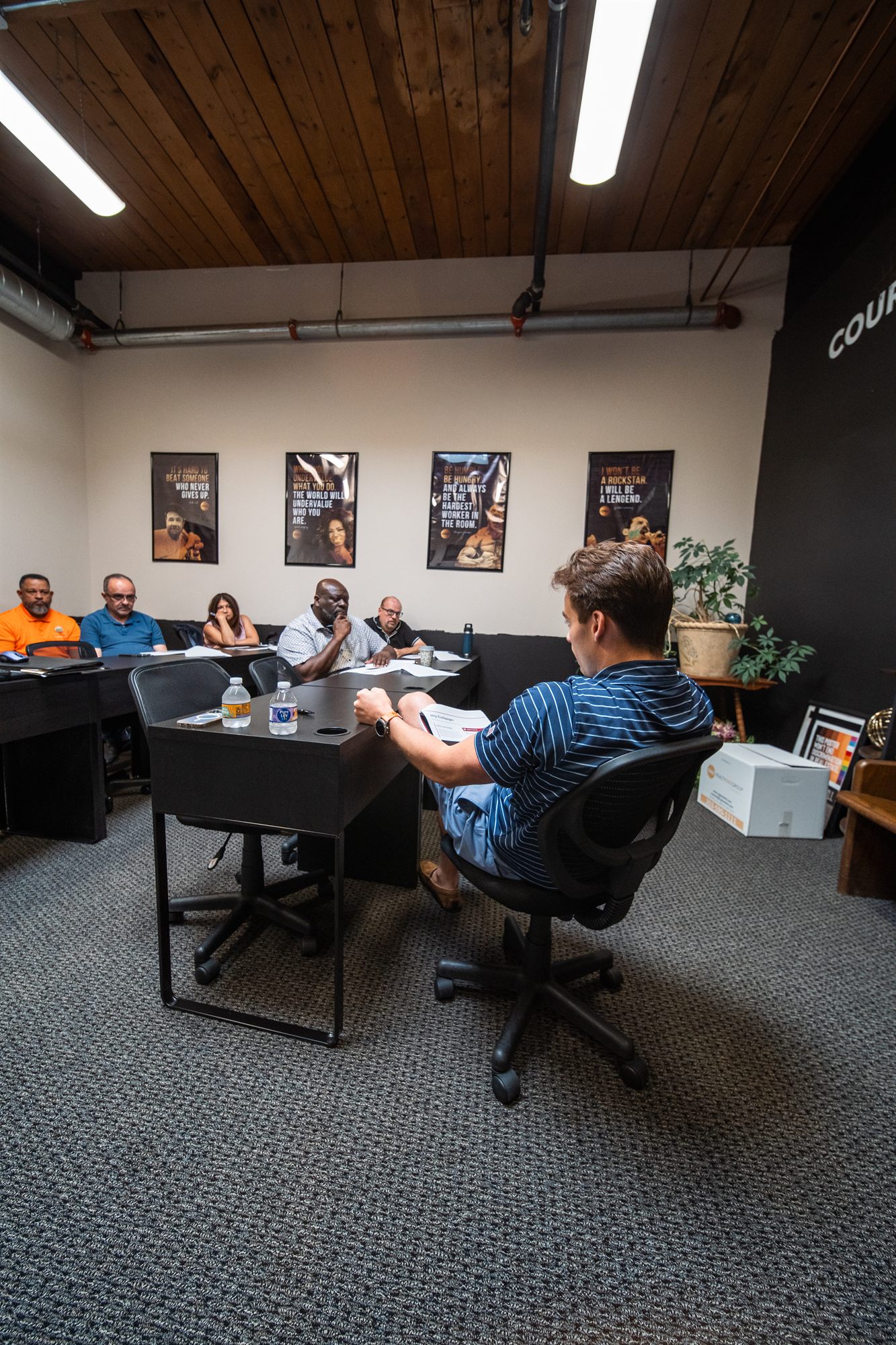 Gaetano addressing Realty One Group agents seated along the training-room wall