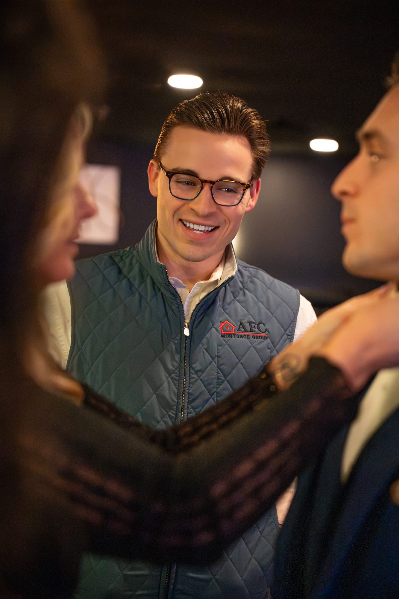 AFC team member in a quilted vest chatting warmly between two guests