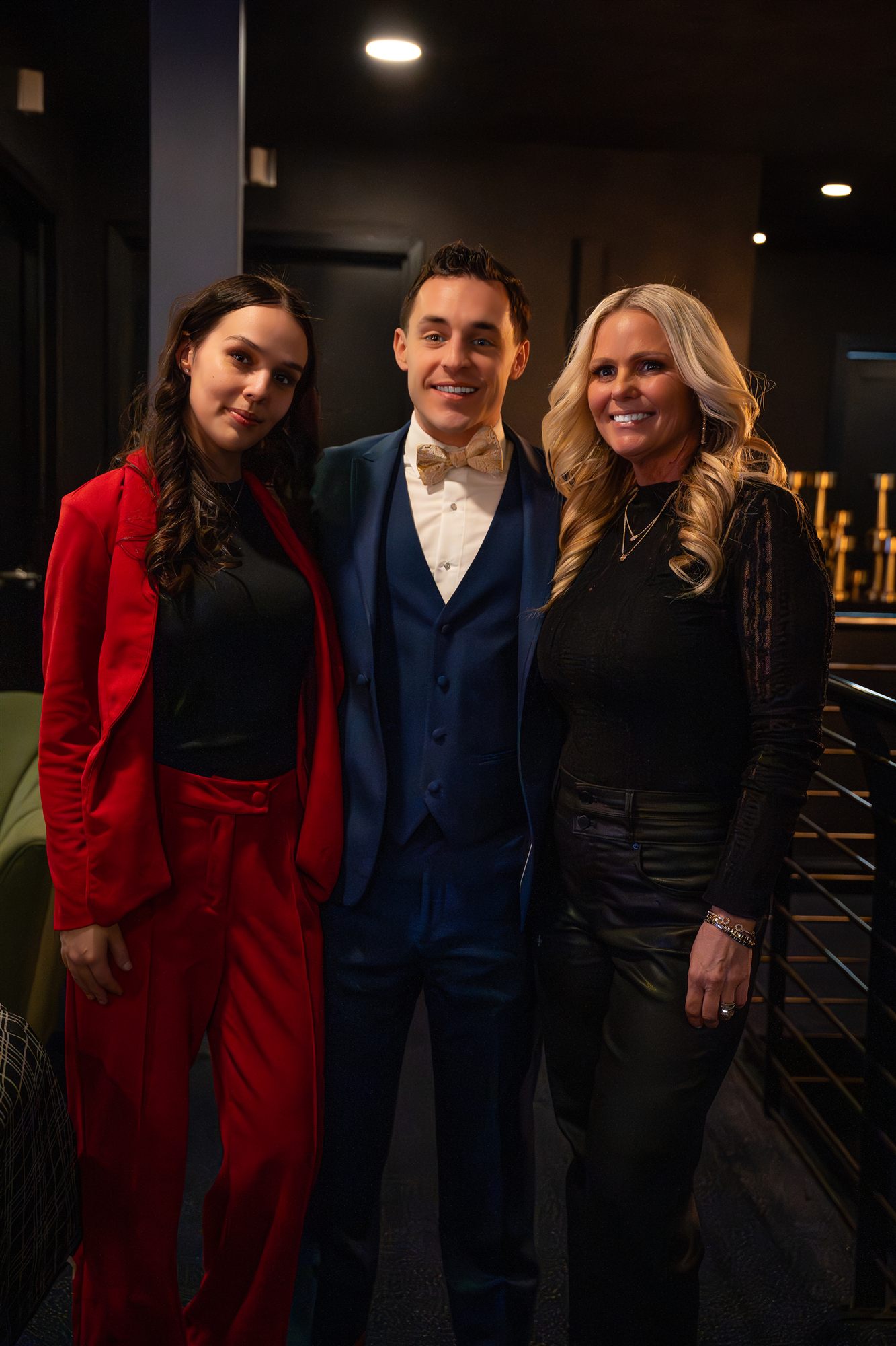 Three guests in a red suit, blue tuxedo, and black dress posing together