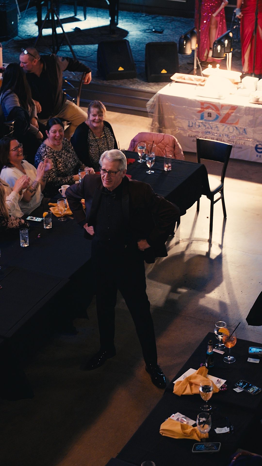 Silver-haired model strutting past cheering tables on the runway