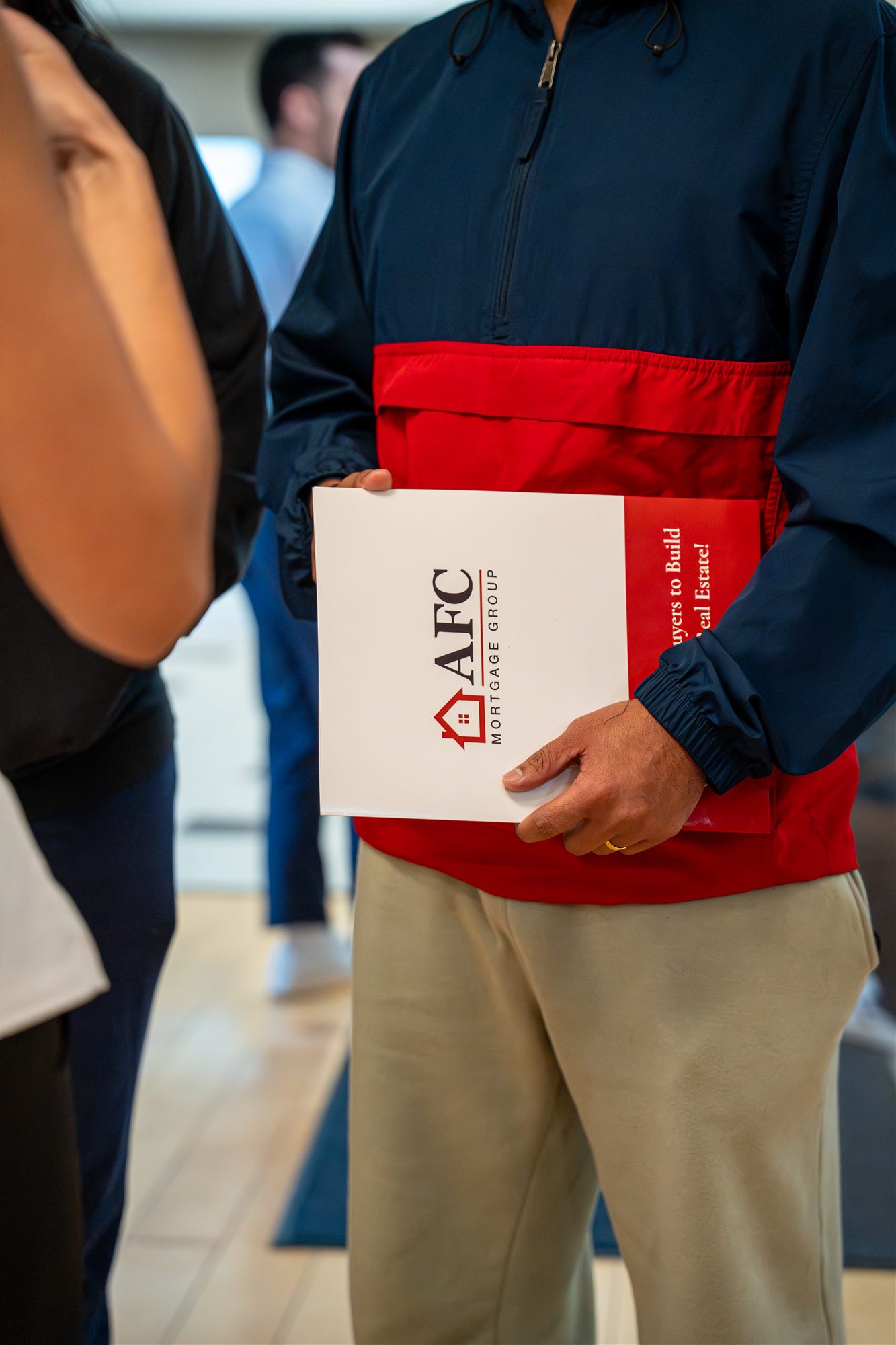Close-up of an attendee holding a branded AFC homebuyer folder