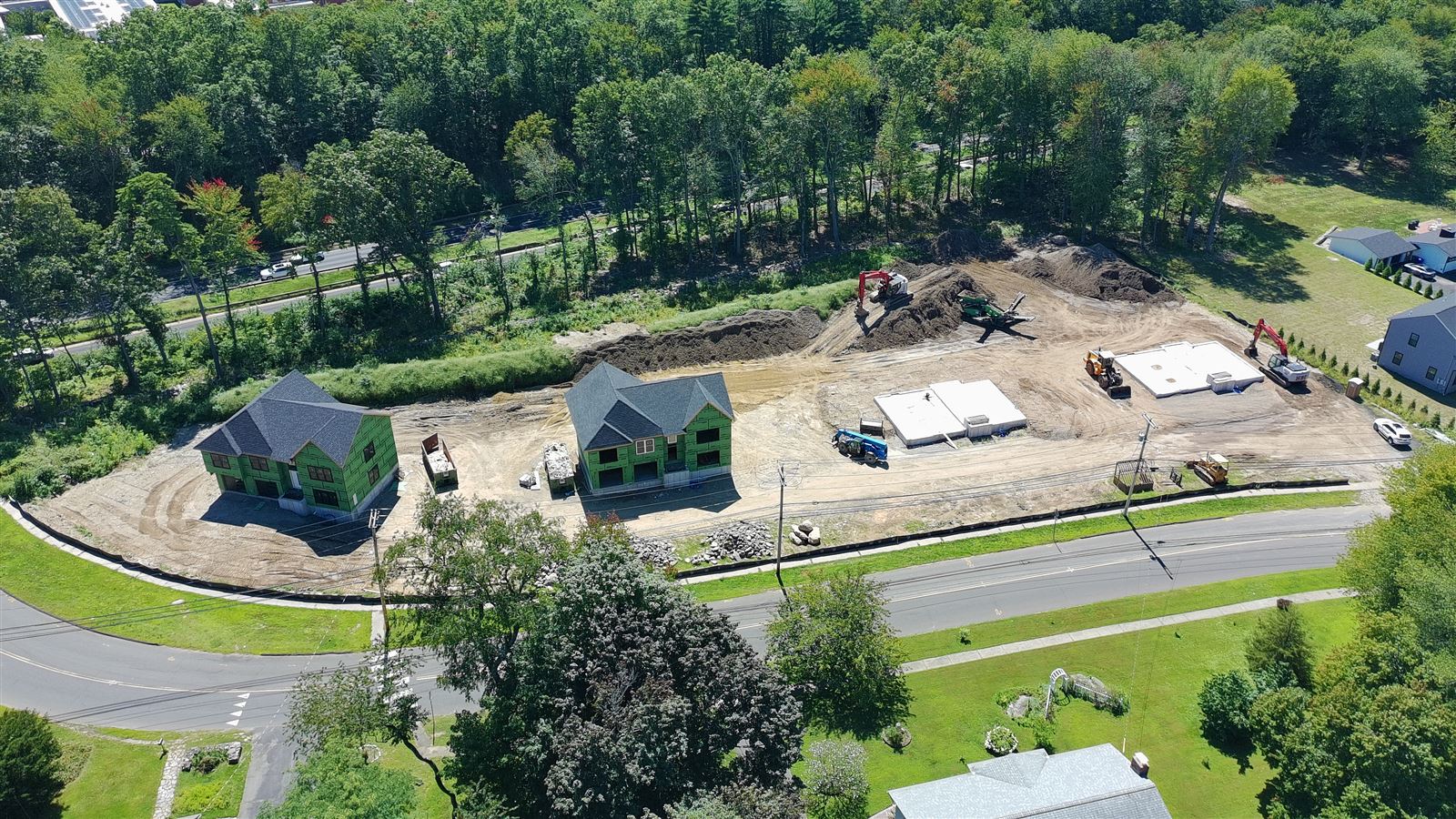 Aerial drone photo over James Farm Road showing all four lots under active construction
