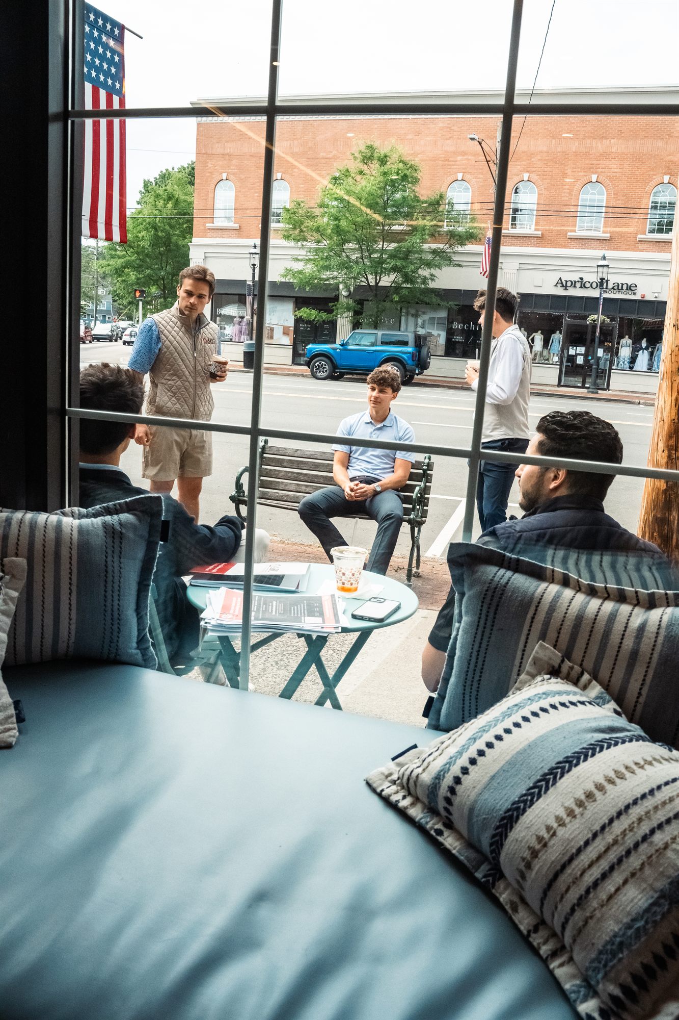 AFC team meeting outside a Main Street cafe with American flag overhead