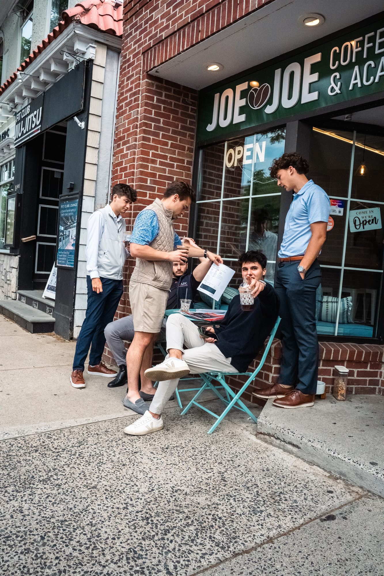 AFC team reviewing paperwork over iced coffee outside Joe Joe's
