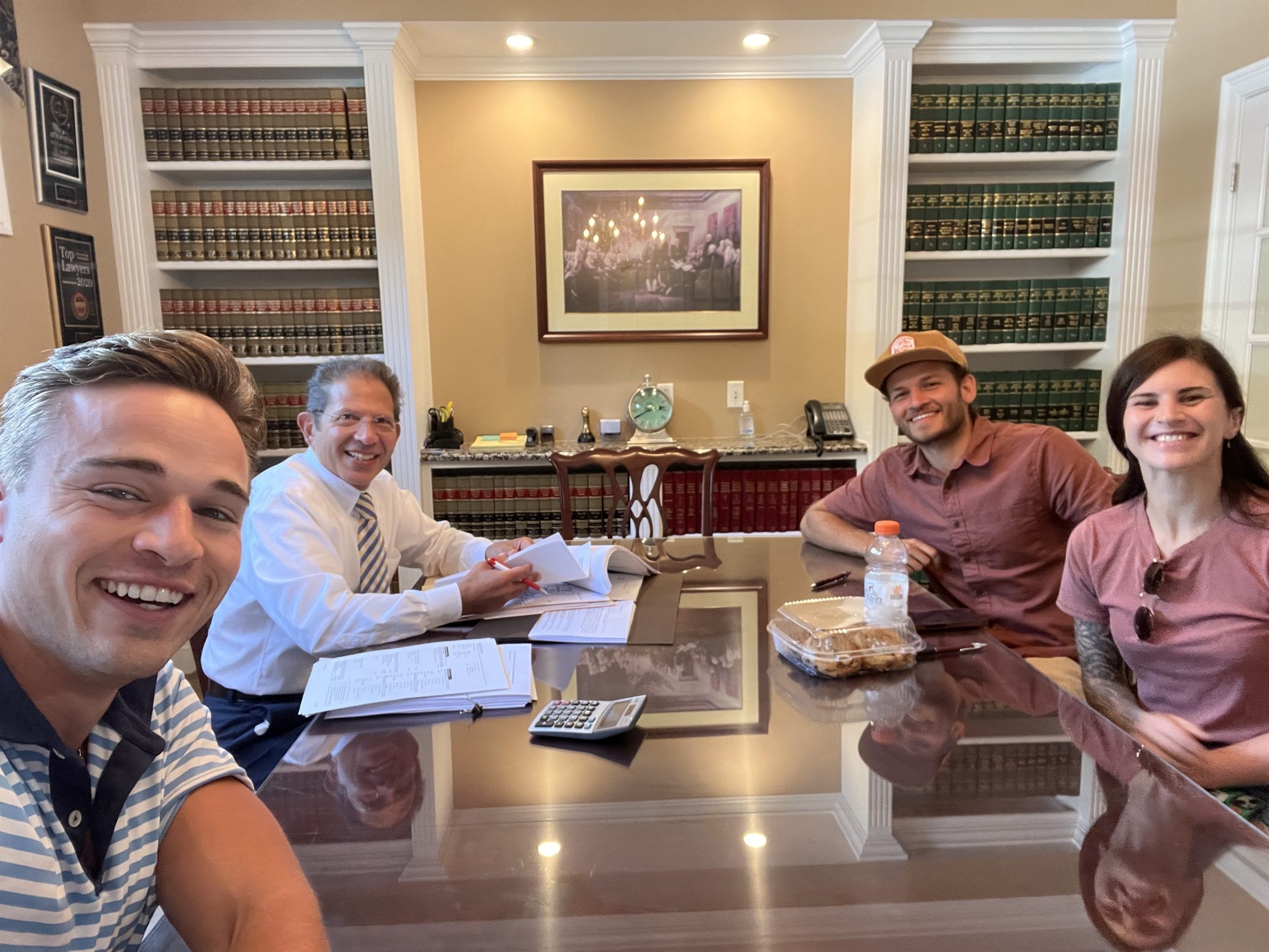 Brendan and the team smiling around the closing table with documents