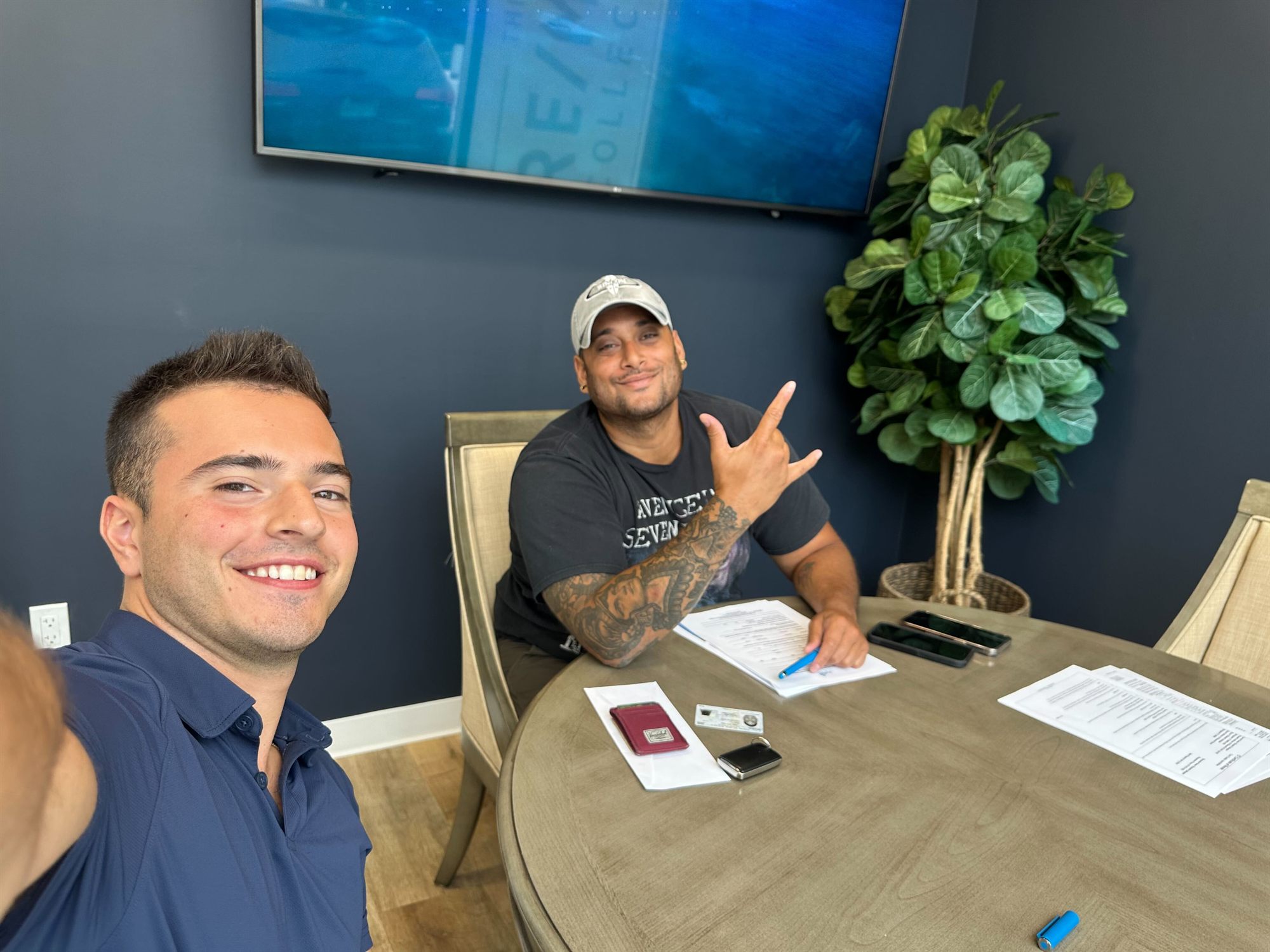 Niko celebrating with a hand sign over the closing paperwork