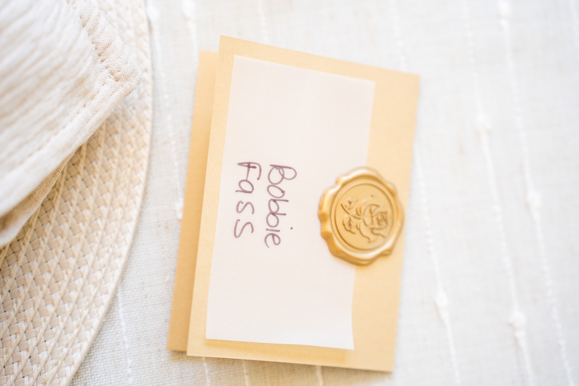 Wax-sealed place card reading Frank Ciambriello on a gold table runner