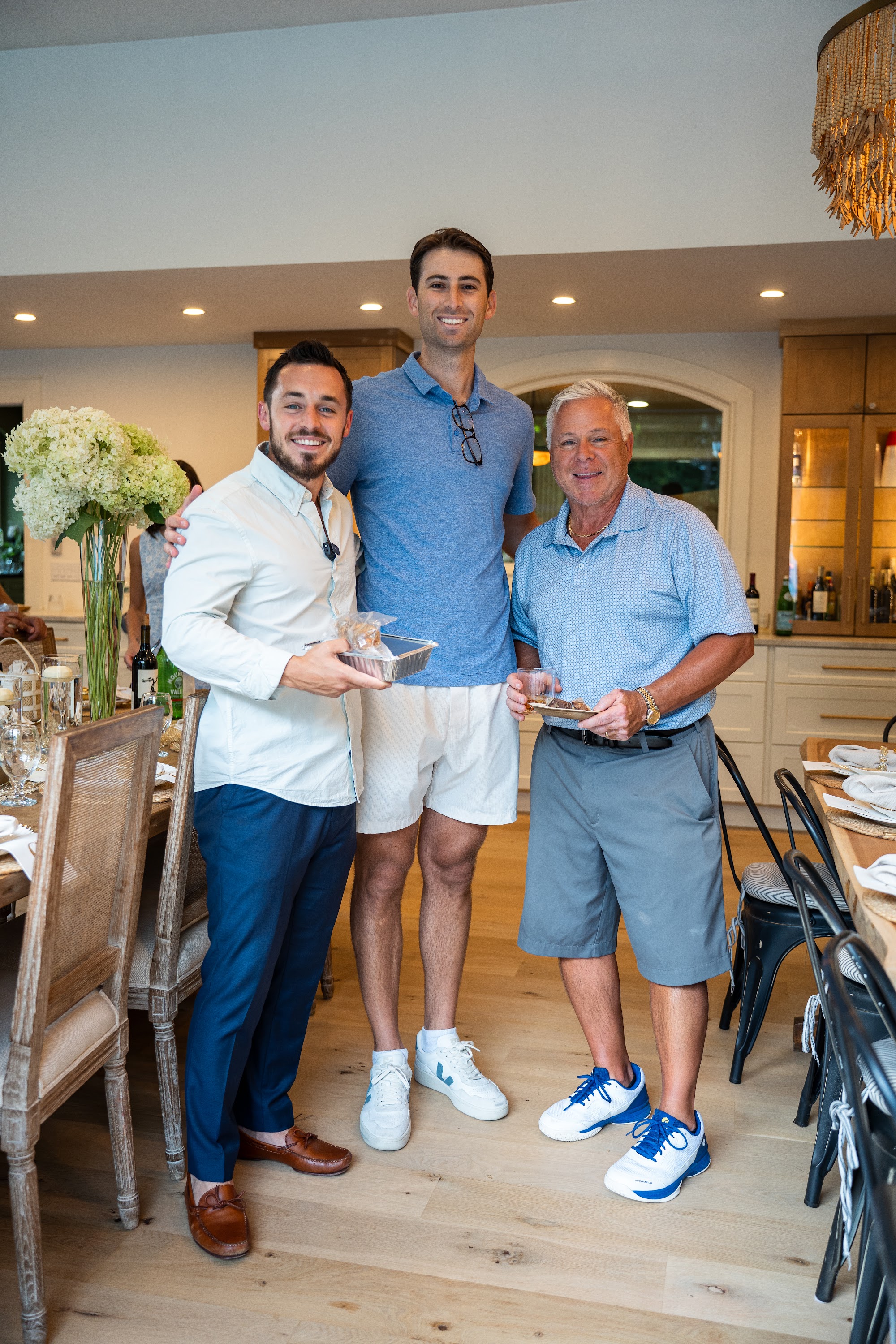 Three guests smiling with small gift boxes in the dining room