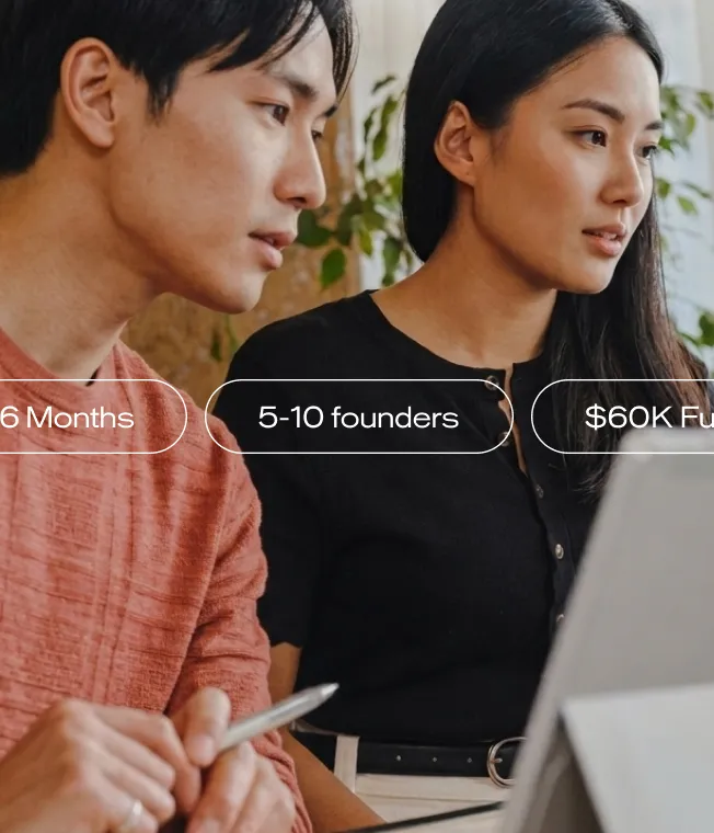 Two focused young adults, a man and a woman, looking at a laptop screen indoors.