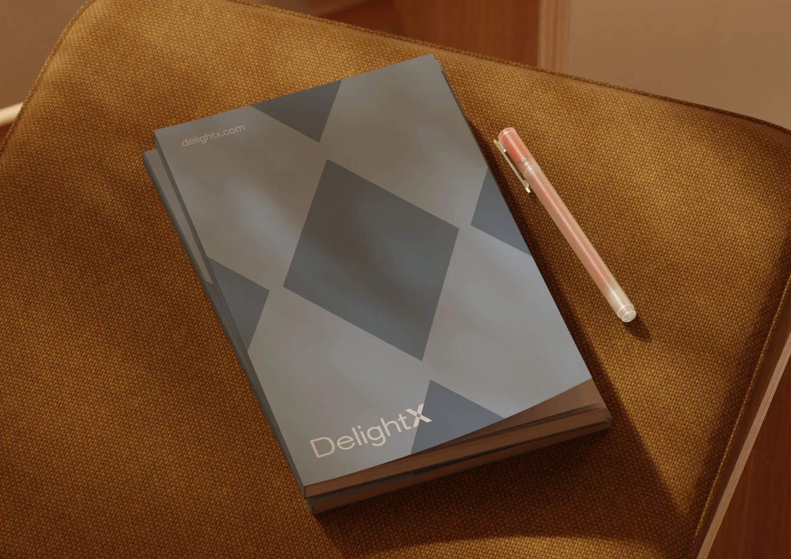 Two gray DelightX notebooks with geometric covers on a brown fabric surface next to a pink pen.