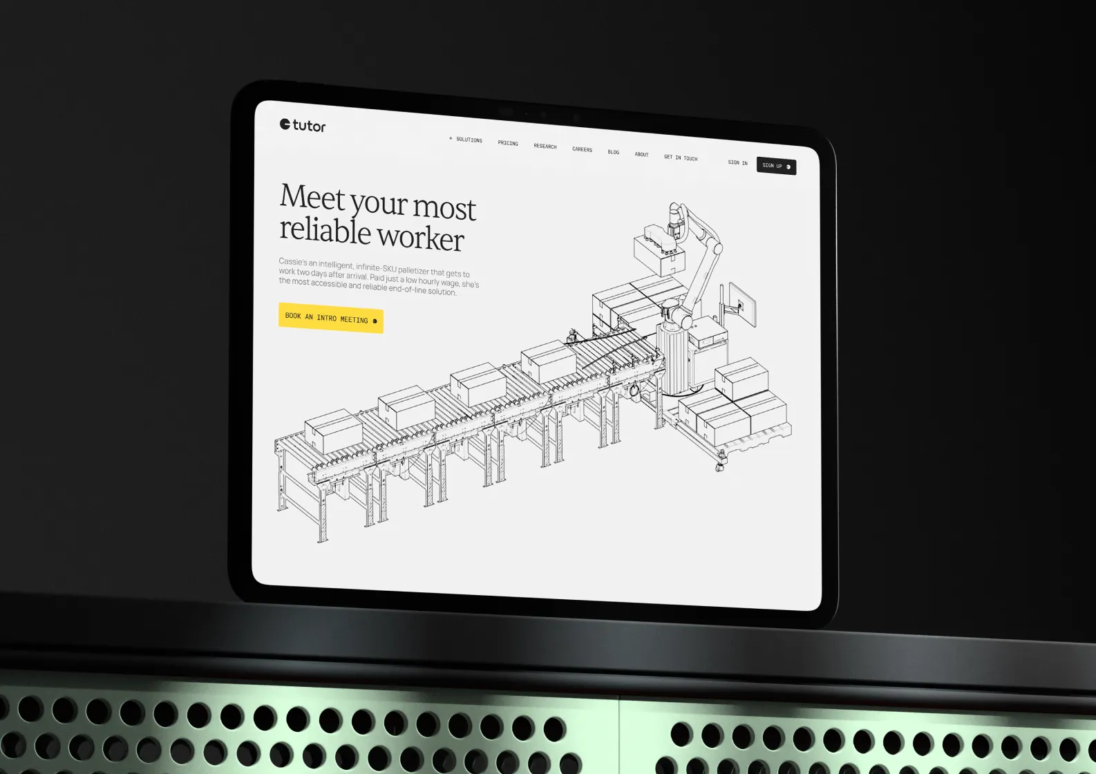 Tablet screen showing a website about an automated palletizer named Cassie with a conveyor and robotic arm illustration.