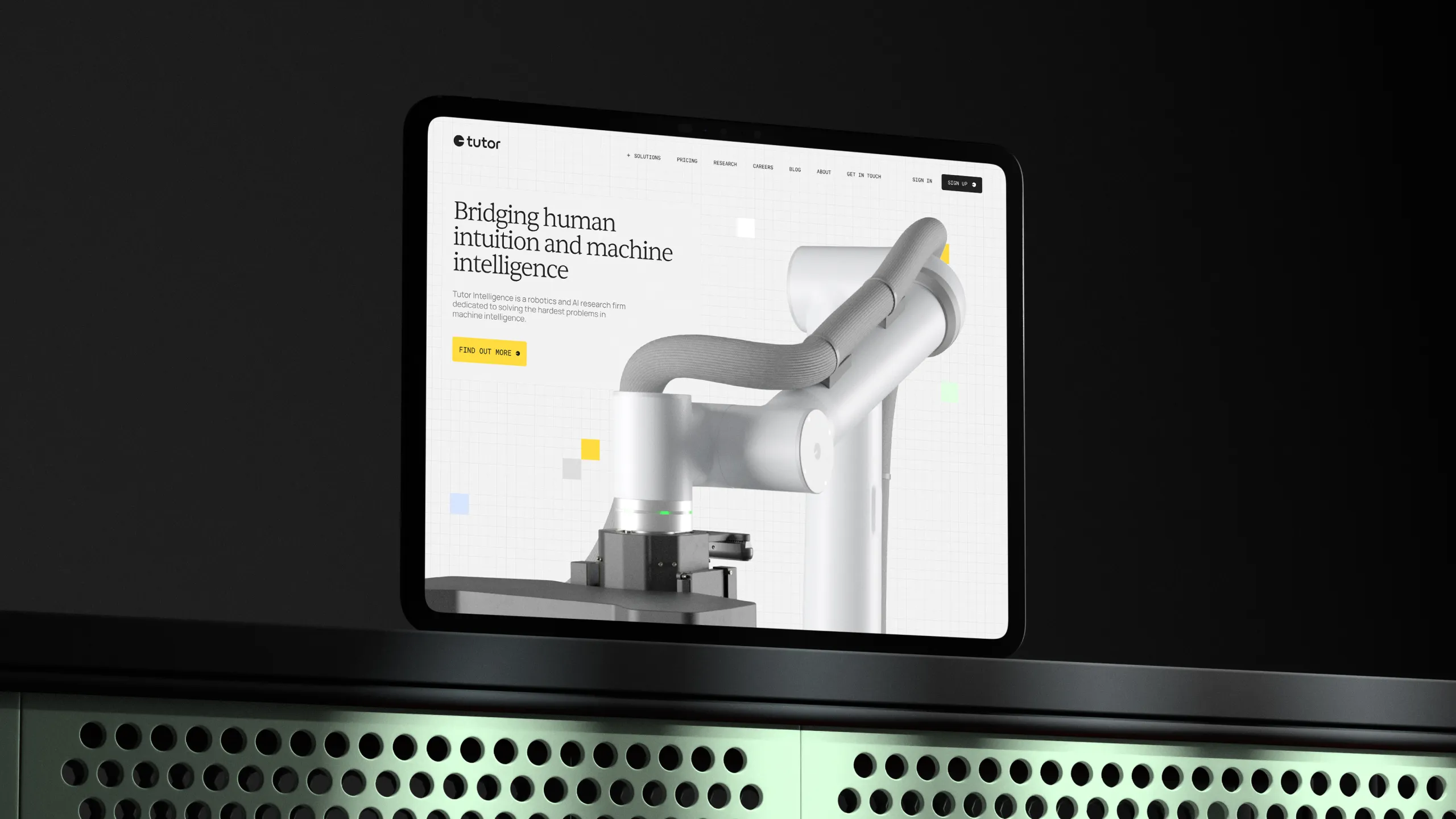 Tablet screen displaying Tutor Intelligence's website homepage with a robotic arm image and text about bridging human intuition and machine intelligence.