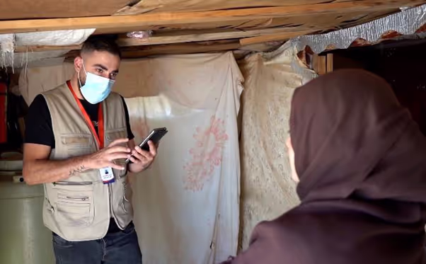 A staff member documents COVID-19 related perceptions on his mobile device while speaking with a woman in a settlement for Syrian Refugees in Lebanon. Credit: Oxfam