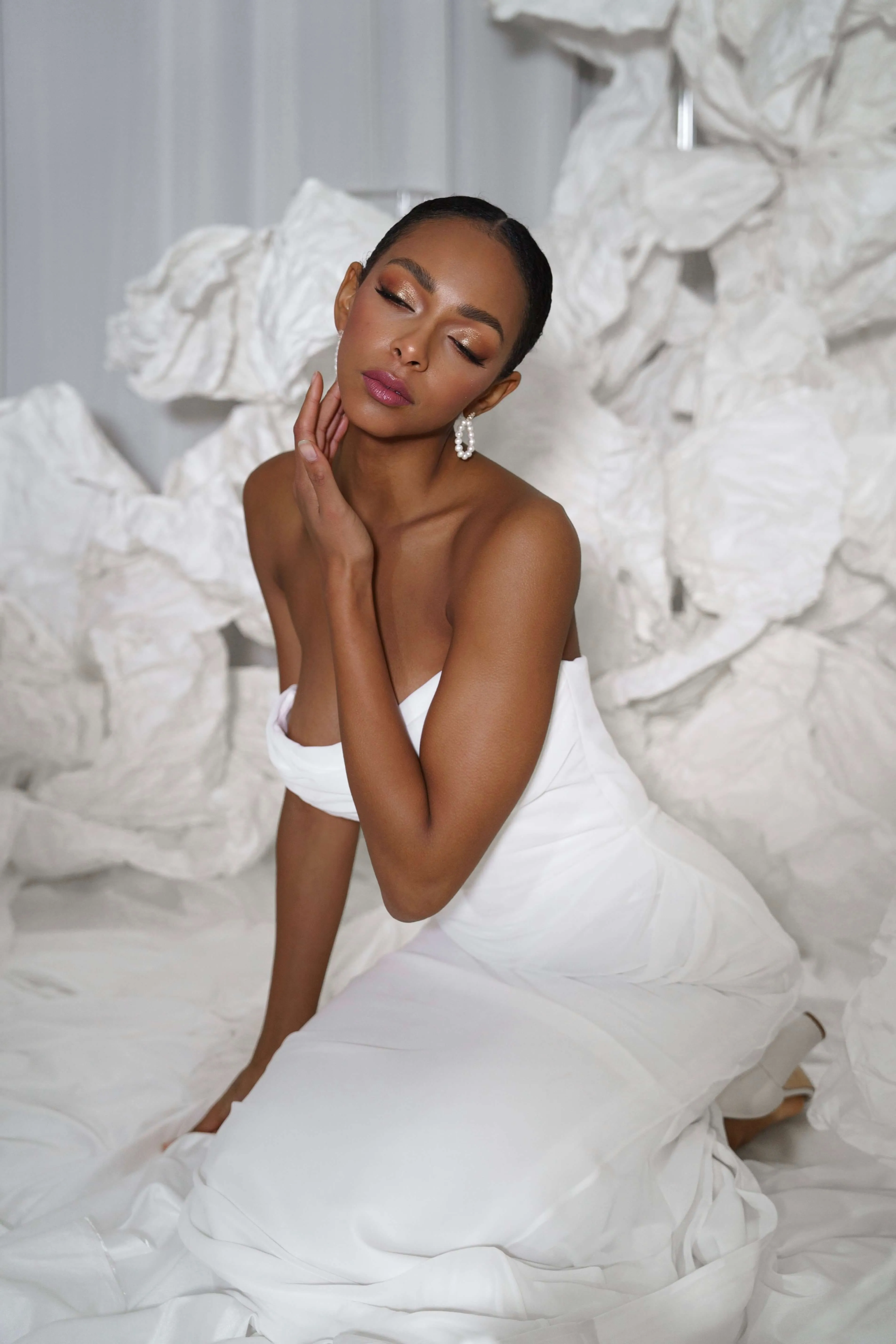 Braut sitzt in einem weißen Hochzeitskleid beim Porträtshooting