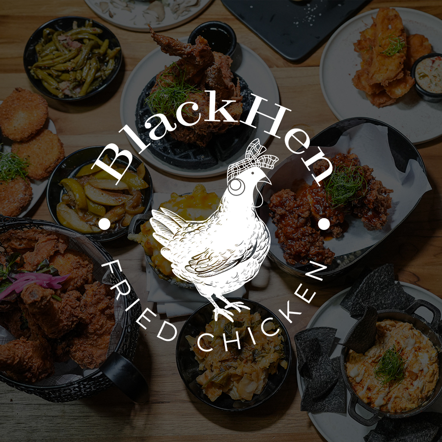 Overhead view of a wooden table with various bowls and plates of Southern-style fried chicken, macaroni and cheese, fried green beans, pickles, relish, and black tortilla chips with dip.