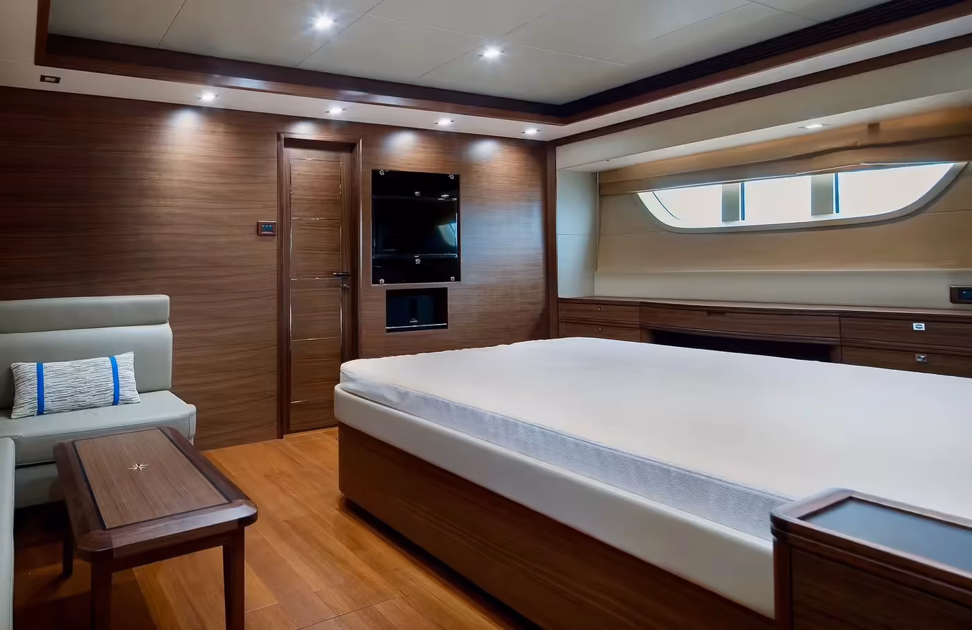 Spacious cabin of a long-range trawler yacht with a large bed, elegant wood paneling, and modern design.