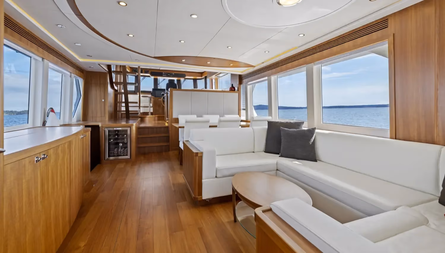 Ocean-capable yachts featuring a bright, modern salon with panoramic windows, white leather seating, and a scenic sea view