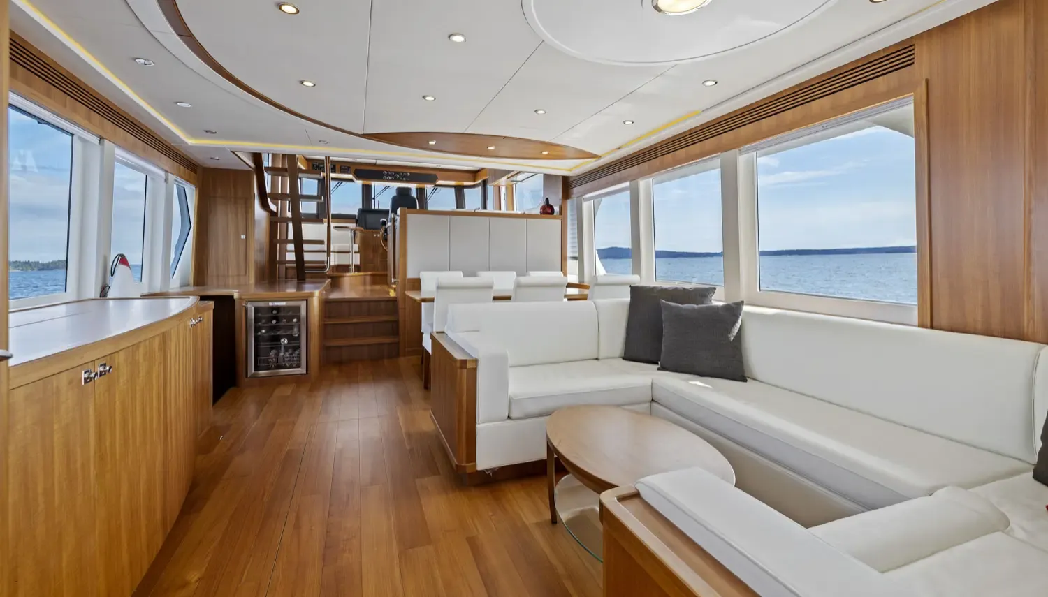 Ocean-capable yachts featuring a bright, modern salon with panoramic windows, white leather seating, and a scenic sea view