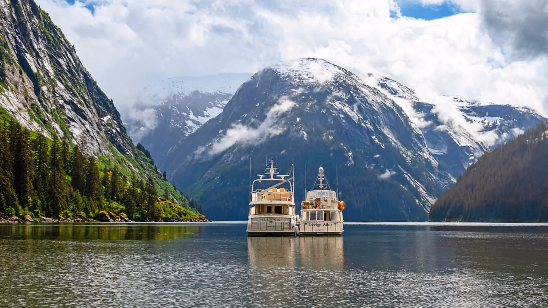 46 classic boats on tranquil lake with snowcapped mountains