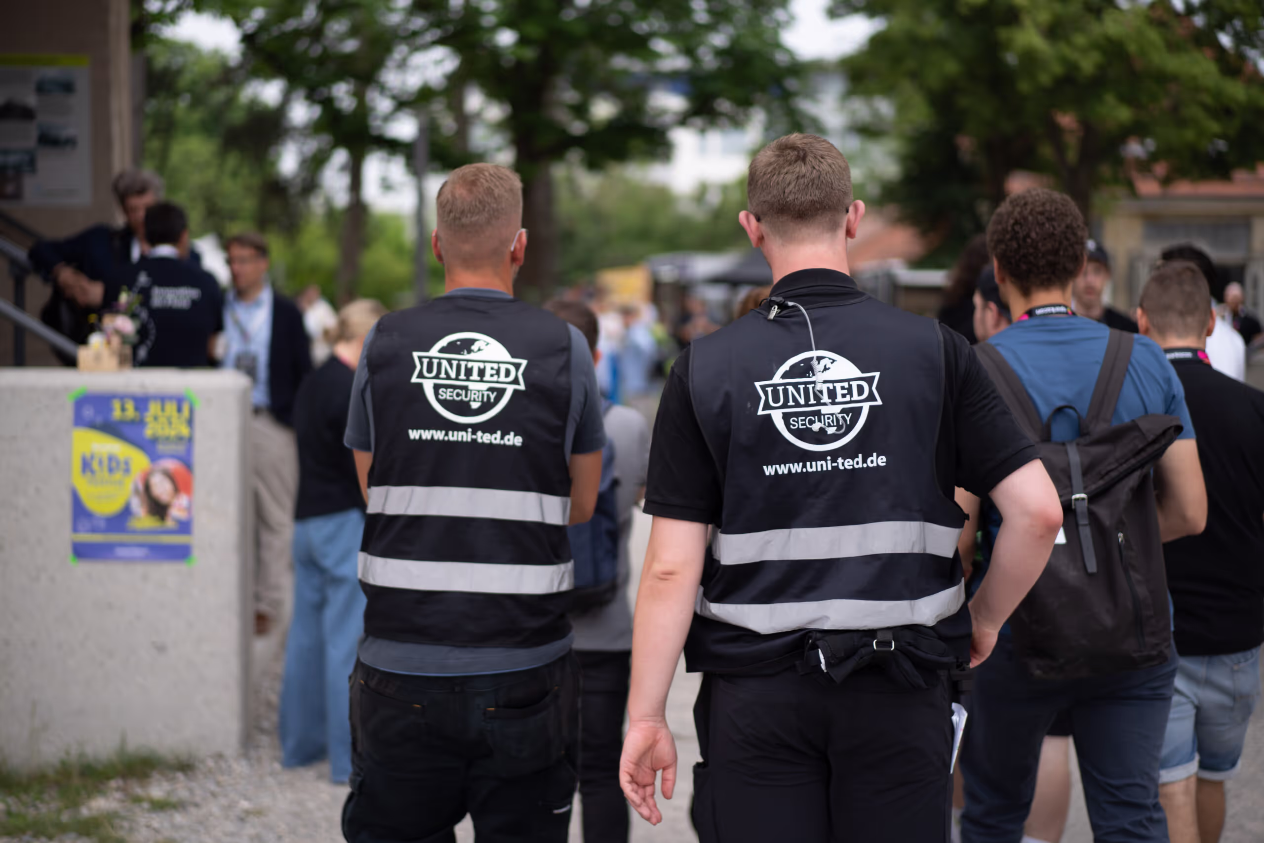 Two men wearing black vests and white shirts.