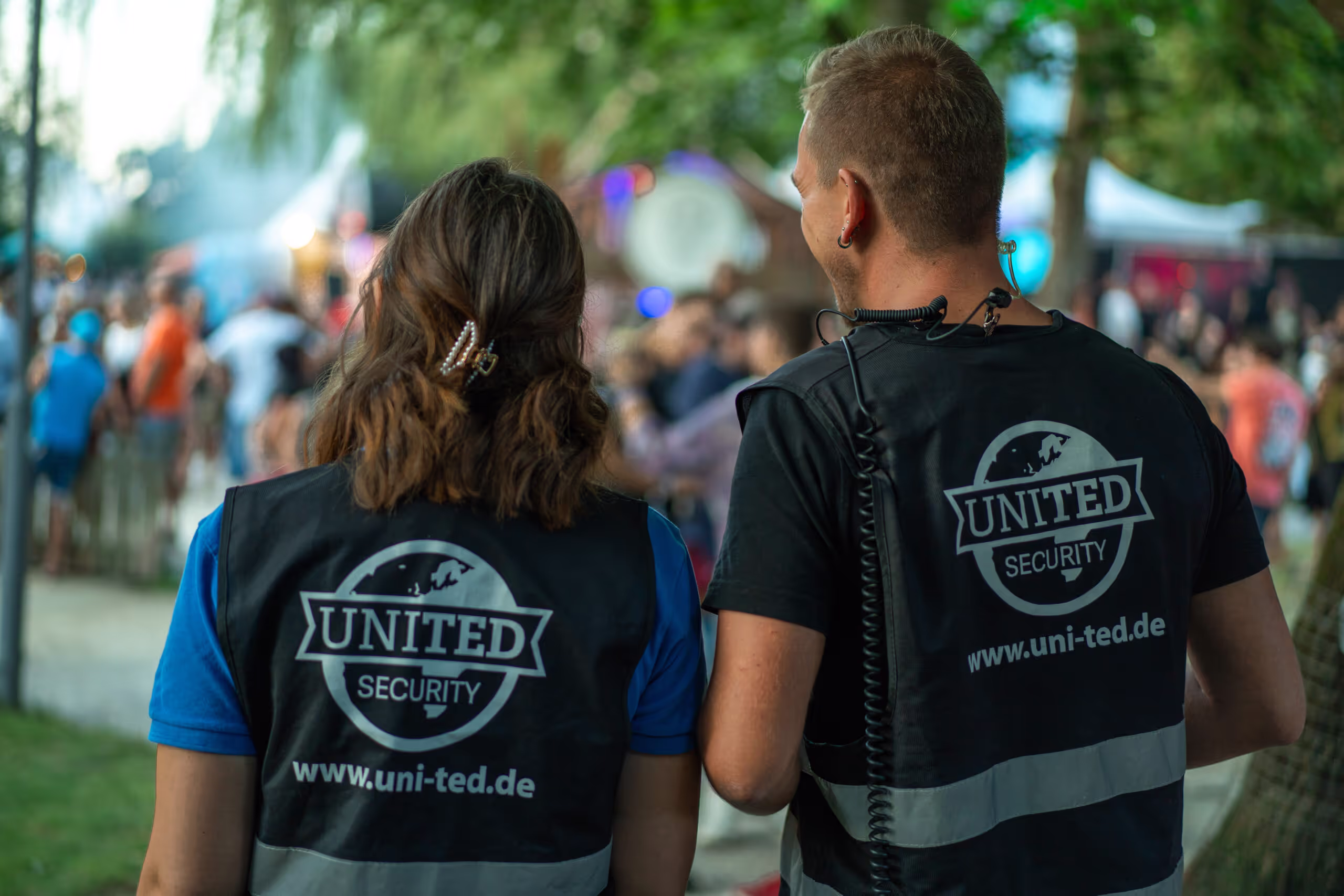 Two people wearing black vests with the word United Security on them.