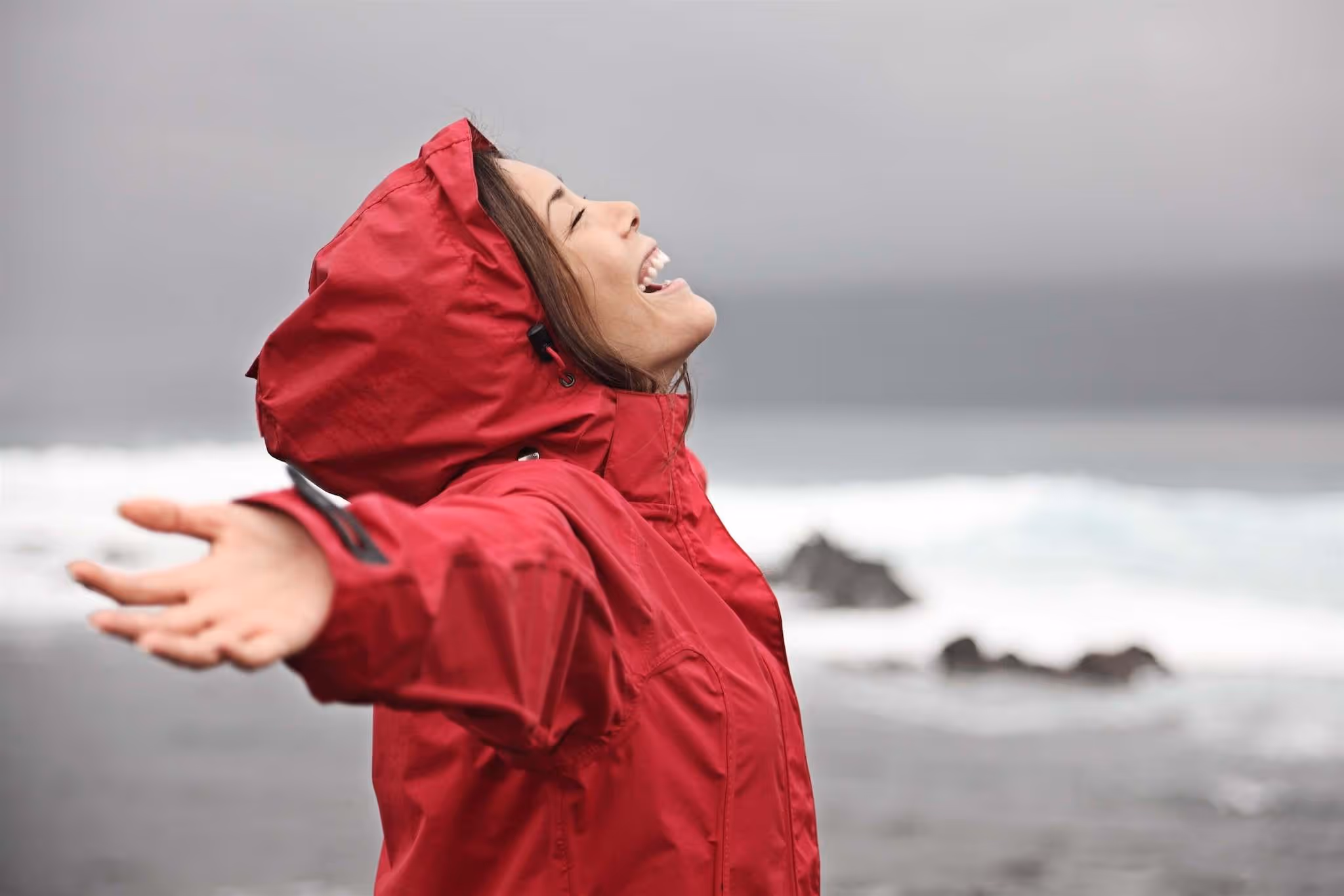 Woman in red rain jacket next to water enjoying the rain falling on her | PerfectWater