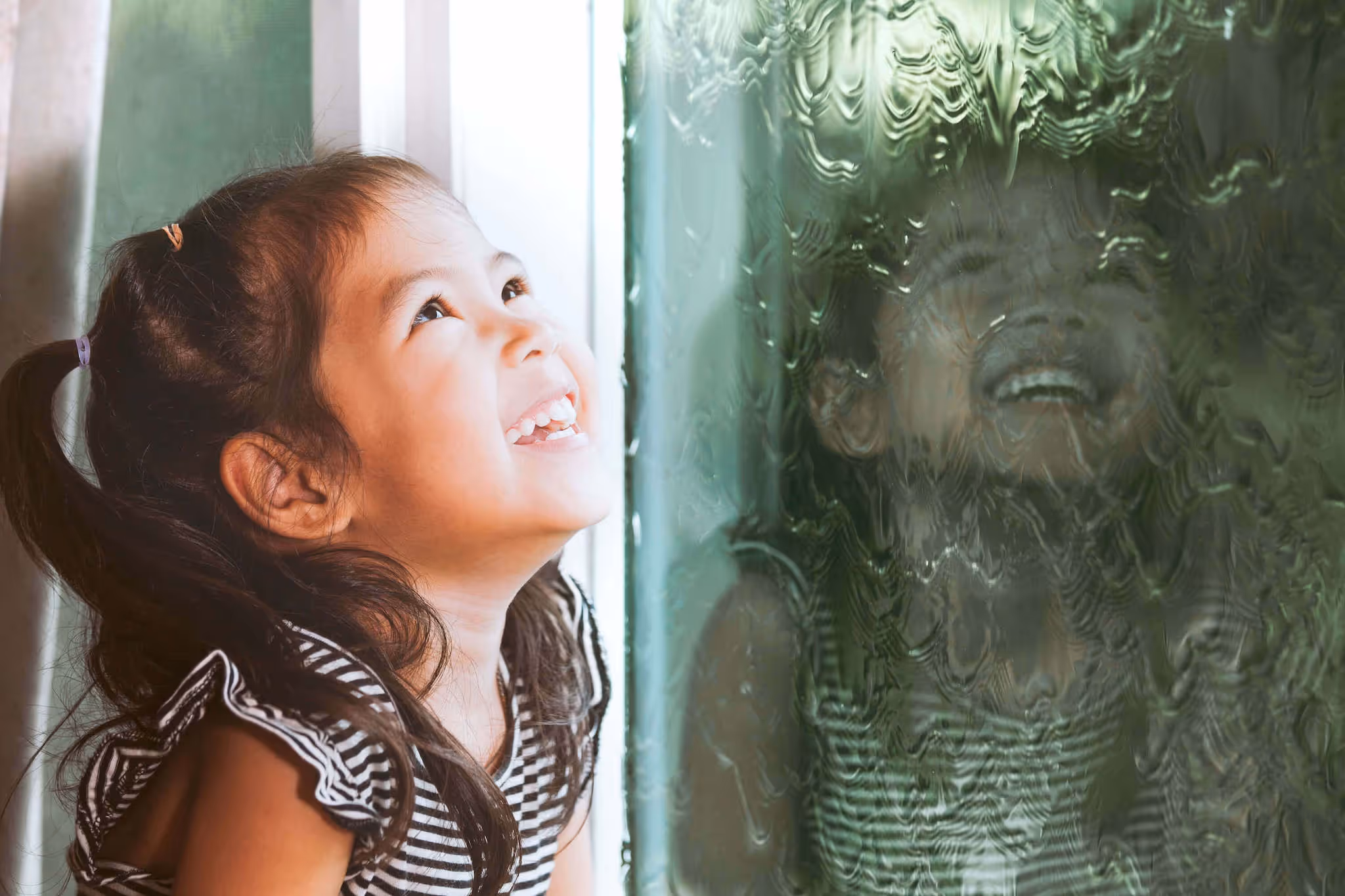 Little girl watching at the window as rain is falling | PerfectWater