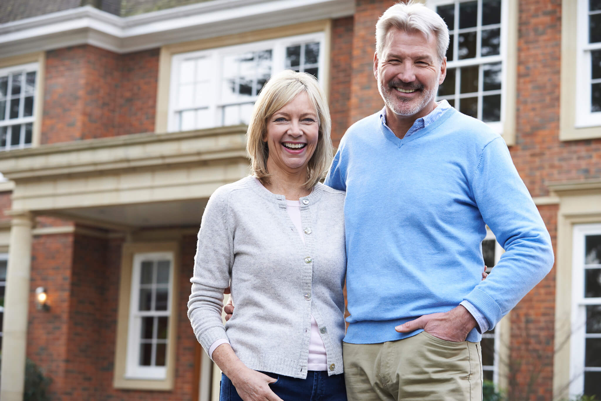 Older couple standing in front of a brick home that has a rainwater catchment system installed | PerfectWater