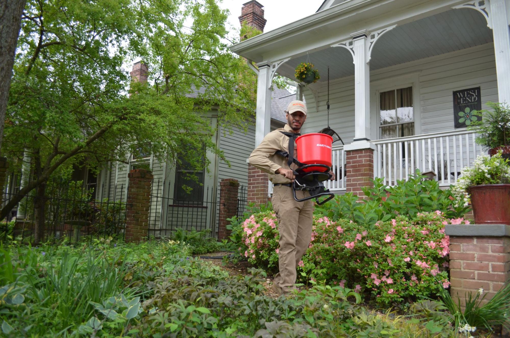 Technician applying organic fertilizer to a residential lawn