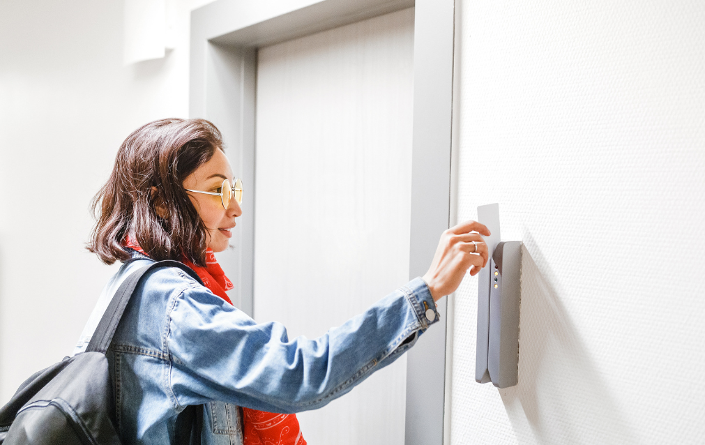 Girl swiping a badge credential at a door.