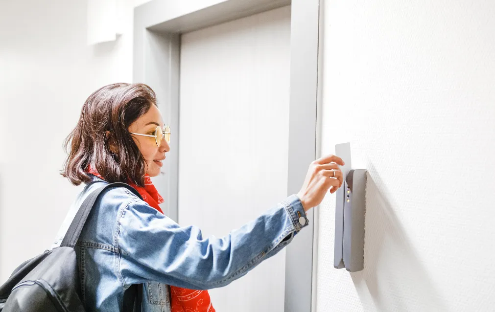 Girl swiping a badge credential at a door.