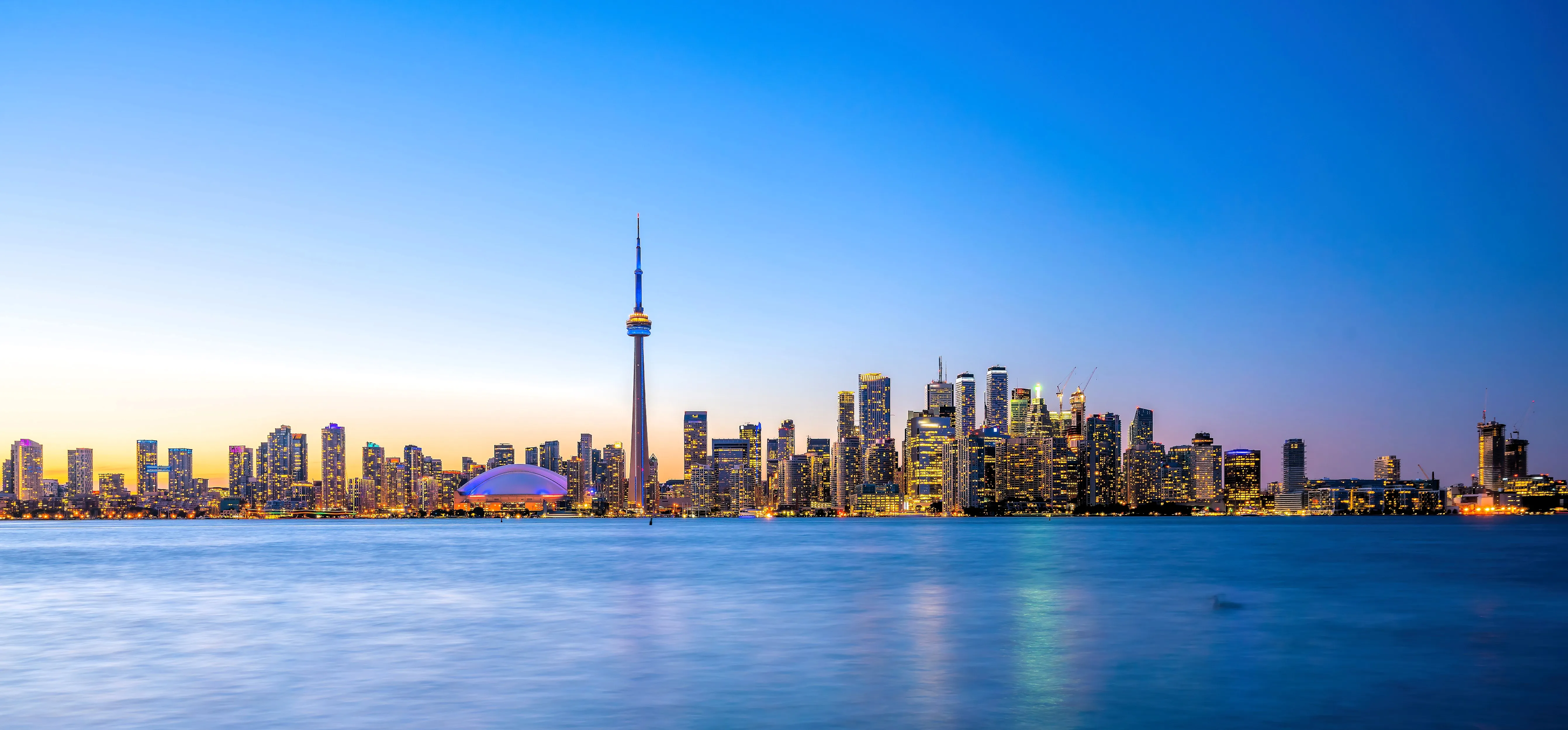 Toronto skyline at dusk with CN Tower and illuminated skyscrapers