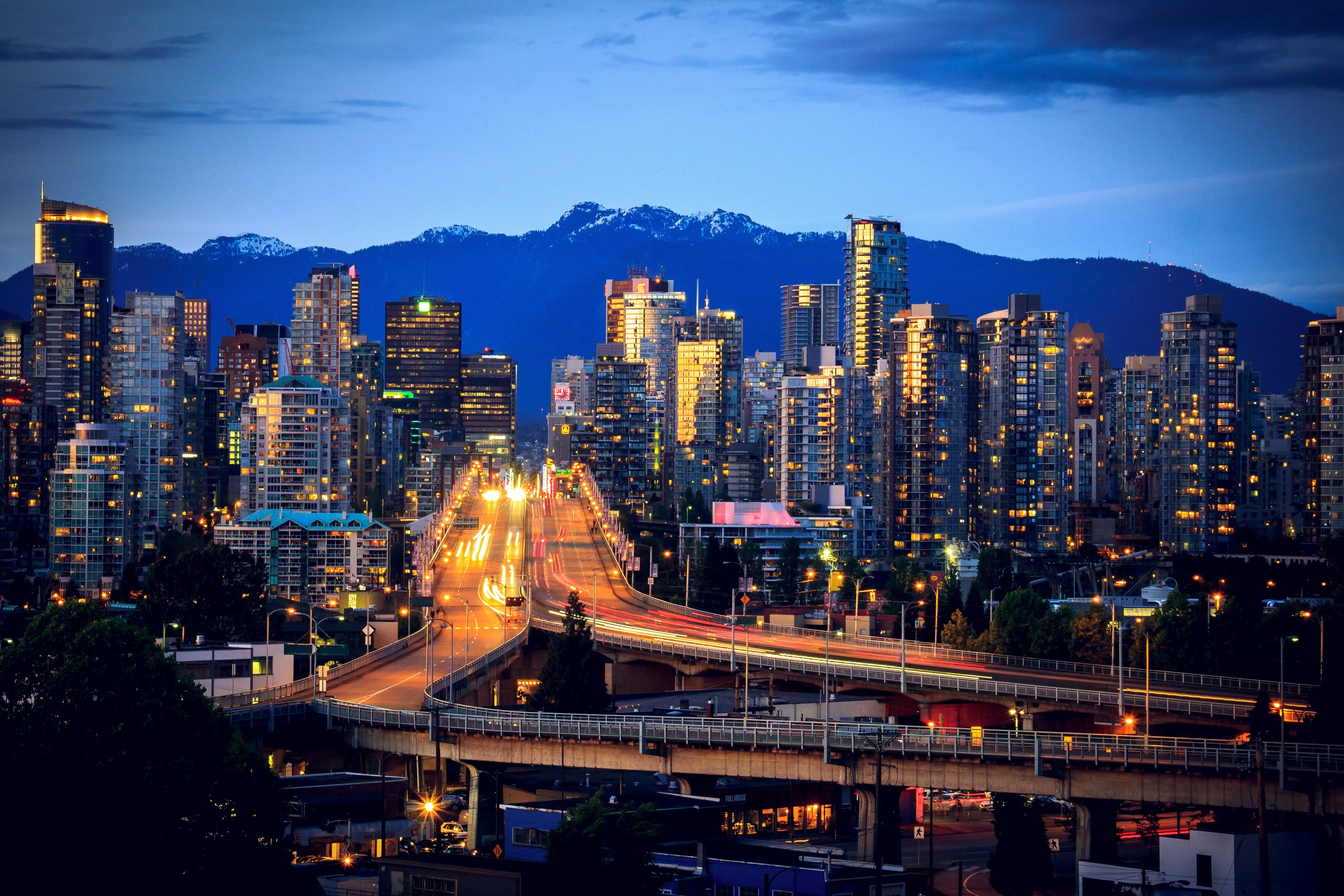 Vancouver skyline at night with illuminated bridge and snow-capped mountains